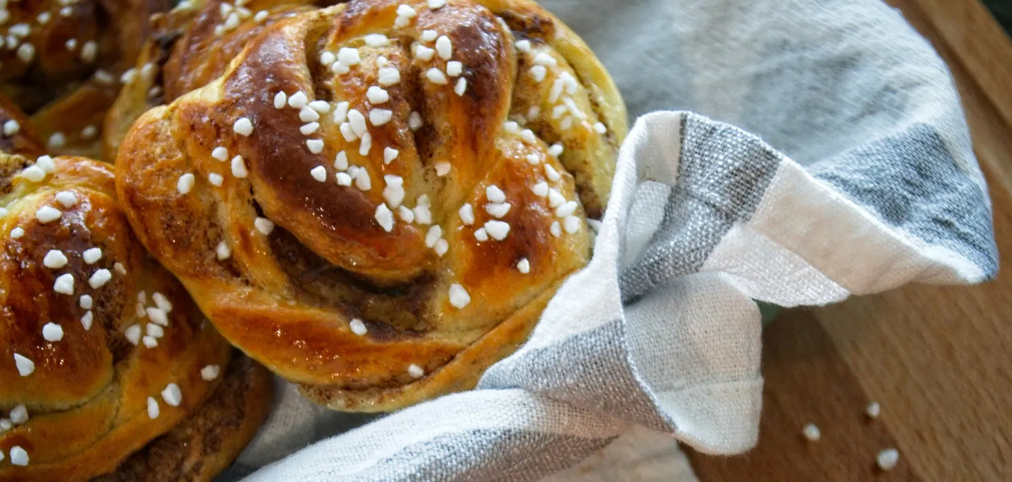 Frisch gebackene Hefeschnecken mit Hagelzucker in einem Tuch auf einem Holztisch