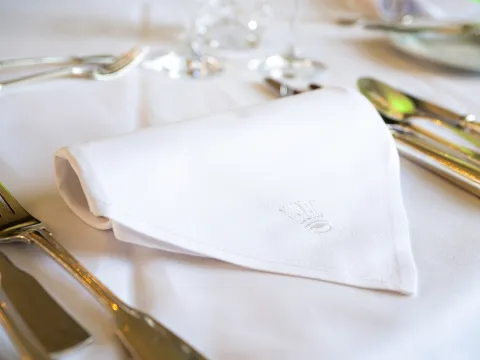 Festlich gedeckter Tisch mit weißer Stoffserviette und Mainau-Emblem