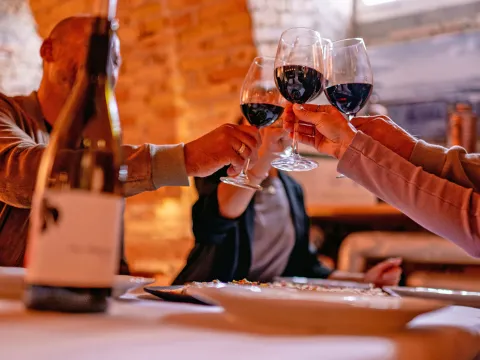 Menschen stoßen mit Rotwein an 