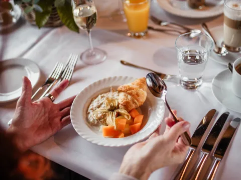 Ein gedeckter Tisch mit Herbstblumen, Sektgläsern und Orangensaft sowie einem Frühstückscroissant
