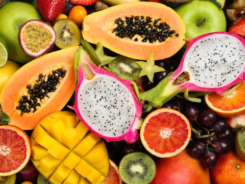 Eine Vielzahl tropischer Früchte, darunter Papaya, Drachenfrüchte, Orangen, Kiwis und Mangos, in leuchtenderen Farben und verschiedenen Formen.